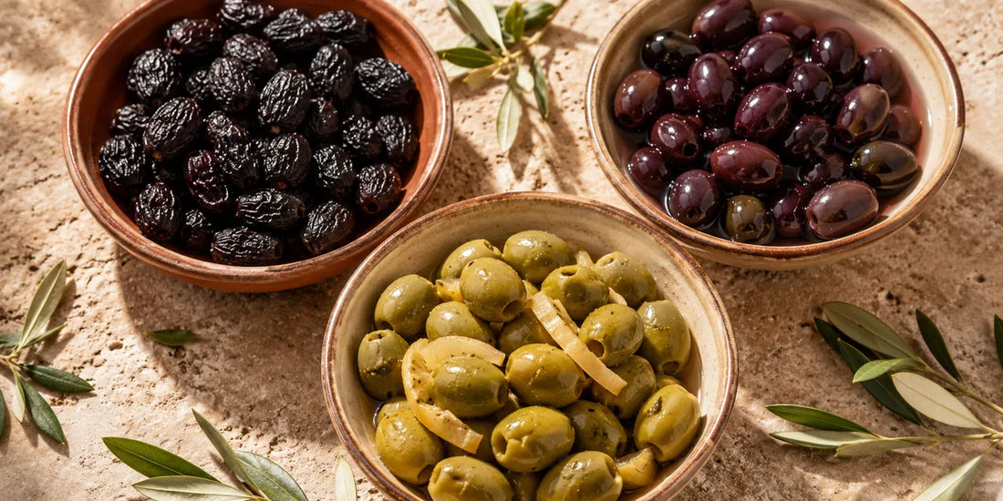 Overhead view of Moroccan olives in terracotta dishes: dry black, glossy purple, and cracked green with preserved lemon