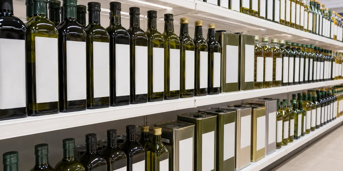 Long supermarket shelf lined with tall unbranded olive oil bottles and tins with blank labels under even light