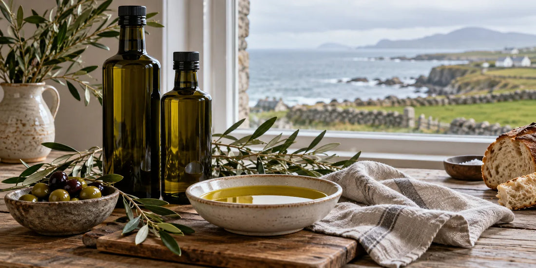 Unbranded dark glass olive oil bottles and tasting bowl in an Irish coastal kitchen with sea beyond