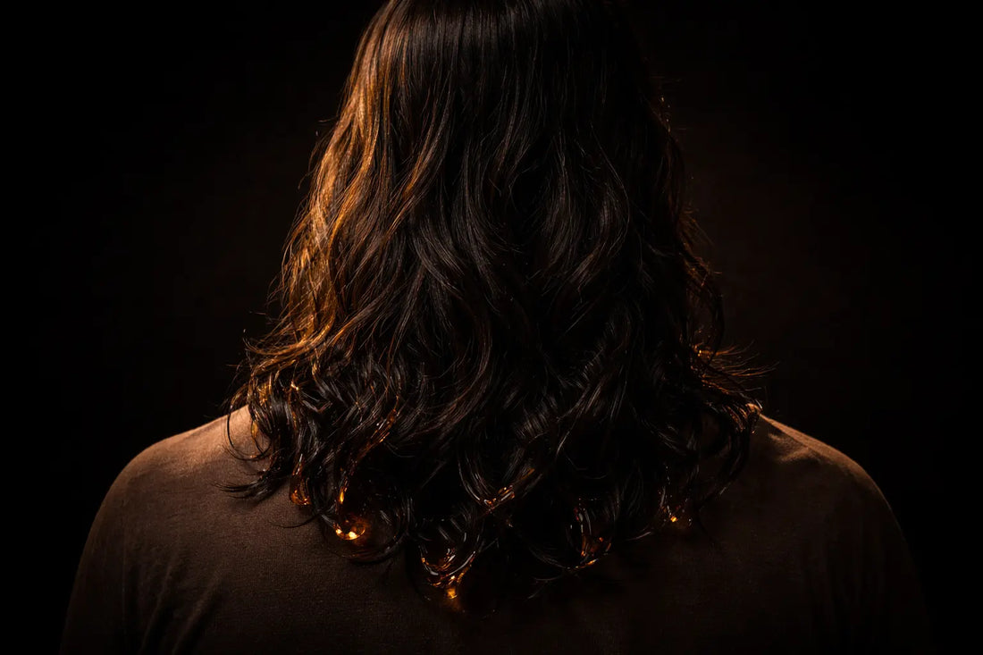 Person with long, glossy dark hair shown from behind, illustrating the effect of black seed oil on hair