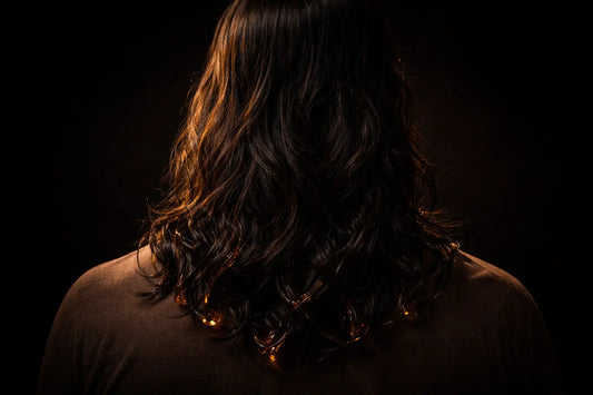 Person with long, glossy dark hair shown from behind, illustrating the effect of black seed oil on hair