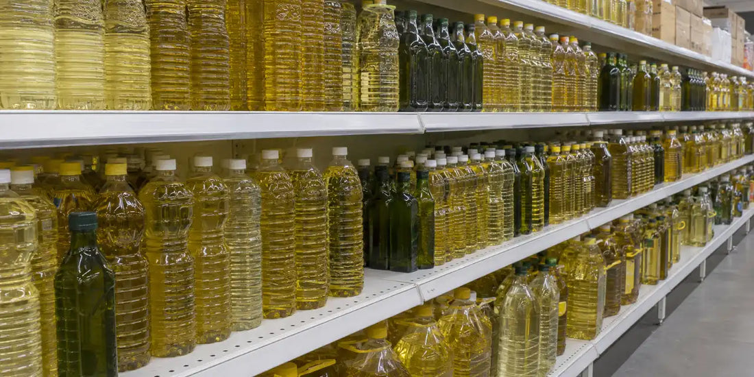 A long supermarket shelf tightly packed with unlabelled clear plastic and green glass cooking oil bottles