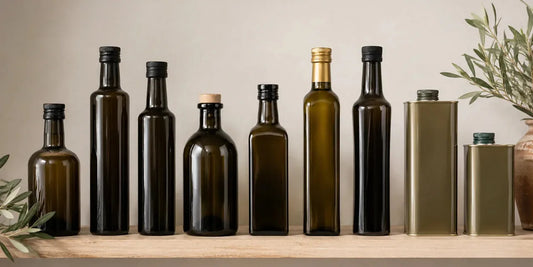 Row of dark olive oil bottles in graduated sizes beside two plain metal tins on a pale shelf