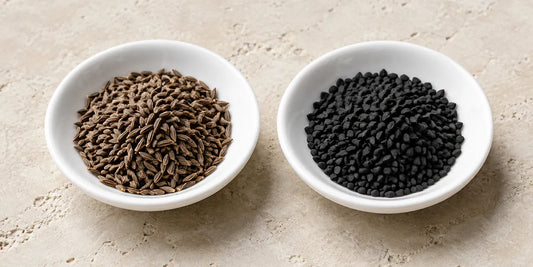 Two unmarked white dishes side by side, one of slender ridged brown seeds, one of angular black seeds