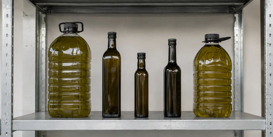 Row of unbranded olive oil bottles and large plastic jugs on a plain metal warehouse shelf in daylight
