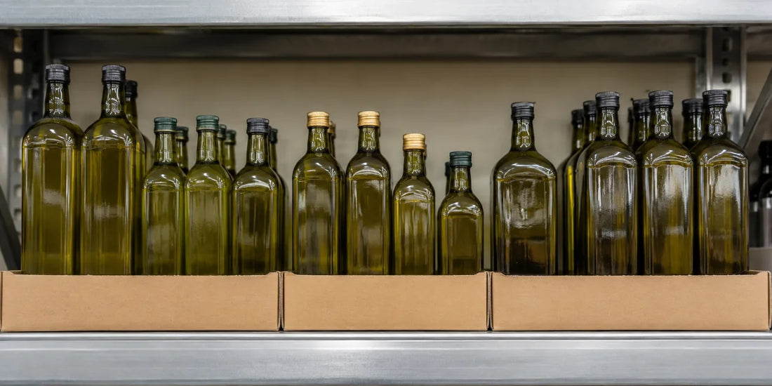 Rows of plain unbranded dark glass olive oil bottles in open cardboard trays on a steel supermarket shelf