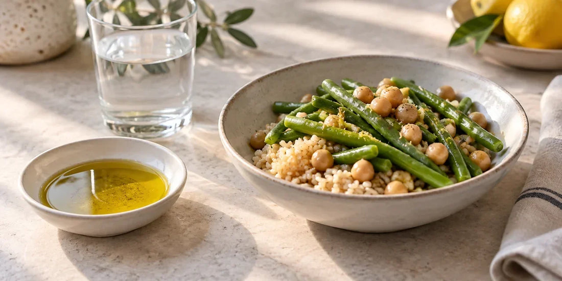 Shallow white dish of rich golden-green olive oil beside a bowl of brown rice, green beans and chickpeas
