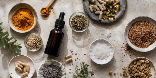 A range of natural supplements in glass bottles and small dishes arranged on a pale stone surface in soft daylight
