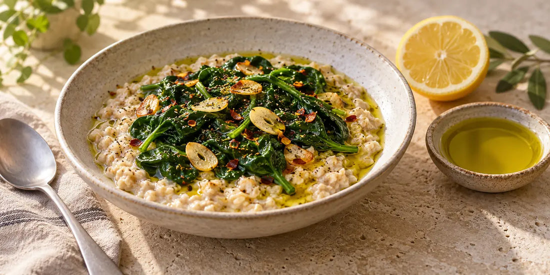 Bowl of creamy savoury oatmeal topped with wilted spinach, garlic and chilli flakes, drizzled with golden-green olive oil