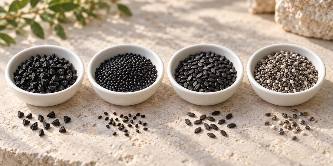Four white dishes of nigella, basil, black sesame and chia seeds in a row on pale limestone