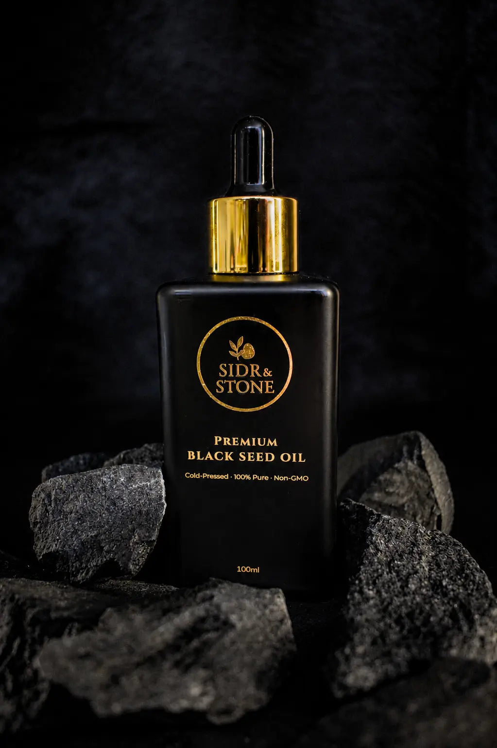Cold-pressed Ethiopian black seed oil in a matte black UV-glass bottle on dark stone